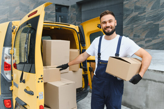 Delivery driver unloading cardboard boxes from yellow van - Powered by Adobe