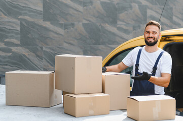 Delivery man showing cardboard boxes near yellow van