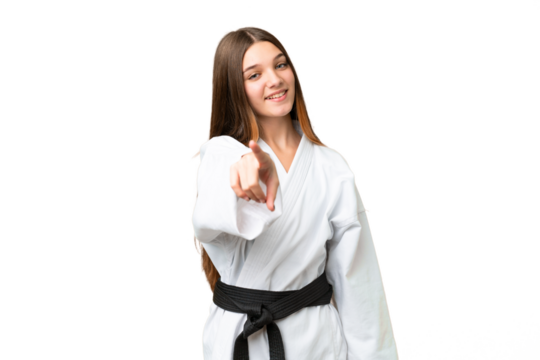 Teenager girl doing karate over isolated chroma key background pointing front with happy expression