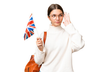 Teenager student caucasian girl holding an United Kingdom flag over isolated background having...