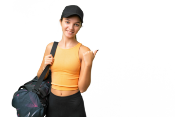 Teenager caucasian girl with sport bag over isolated background pointing to the side to present a product