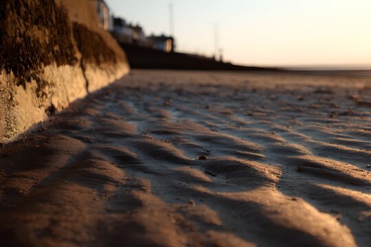 Golden light reflecting off the rippled sand on the beach during sunset - Powered by Adobe