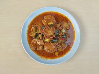 Semur jengkol or dogfruit with spices on plate with wooden table background, Flat lay. Indonesian food 