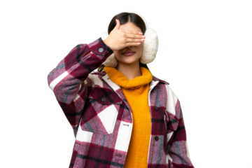 Young Russian woman wearing winter muffs over isolated chroma key background covering eyes by hands. Do not want to see something