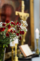 Altar with red flowers and golden crucifix — Christian church interior with bouquet, candles, open Bible, and warm spiritual atmosphere