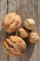Walnuts of different sizes on an old wooden background. Top view. Healthy food.