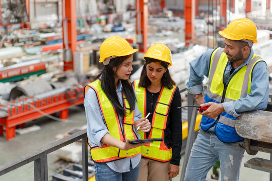 engineer worker woman man in safety vest and helmet check material with blueprint, people working in industrial manufacturing factory planning to inspect repairing equipment in production warehouse