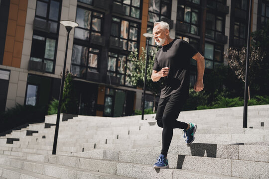 Elderly bearded man running up stairs in an urban city park during an outdoor morning workout showcasing fitness health and active lifestyle in a modern city setting