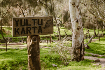 Wooden sign of the with the text "Yultu Karta" of the Morialta Nature Playground in Morialta Conservation Park outdoor at daytime during spring near Adelaide in Australia.