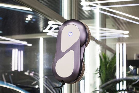 Automated window cleaning robot on a large glass pane in a bright modern apartment. Automatic window cleaning robot washing glass in high-rise building, providing convenience, efficiency for home. 