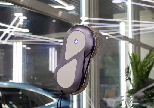 Automated window cleaning robot on a large glass pane in a bright modern apartment. Automatic window cleaning robot washing glass in high-rise building, providing convenience, efficiency for home. 