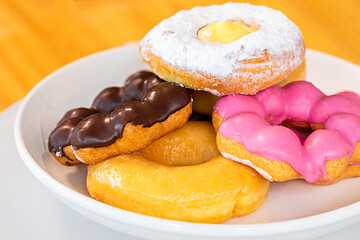 Close-up of sugar-coated donuts on white plate. Studio shot, unhealthy food