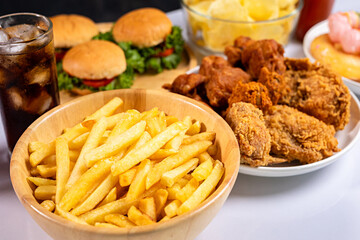 Close-up of unhealthy fast food, hamburger, fried chicken, donuts and french fries on plate.