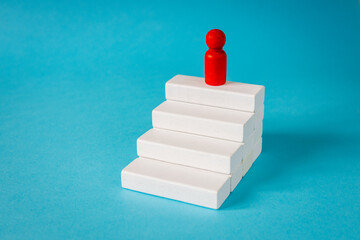 Achieving success. Stages of development. The leader of the organization at the top. White stairs leading up. The path to achieving the goal. Business concept. close up. copy space. Blue background