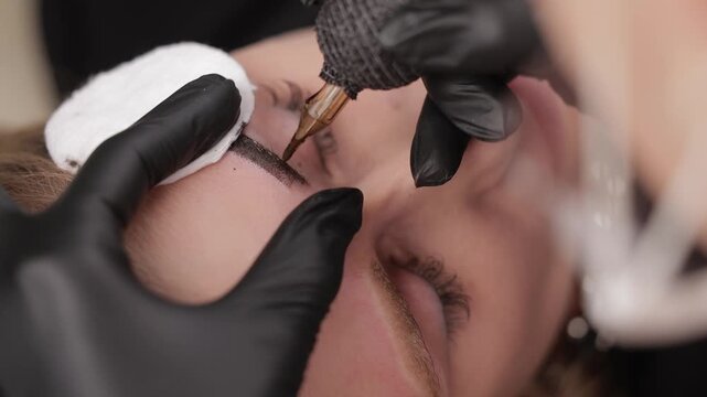 Female eyebrow tattoo procedure closeup for precise microblading permanent.