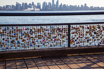 Obraz premium Love Locks locked on the railing with Vancouver skyline background at Lonsdale Quay Market in North Vancouver, British Columbia, Canada.