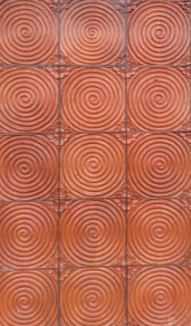 Texture of terracotta or cement tile in reddish-brown color with a spiral circle pattern.
