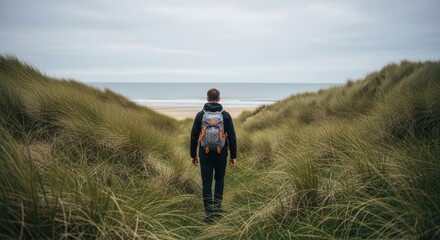 Male adult hiker with a backpack walking on a coastal path. Adventure travel and outdoor lifestyle concept. Exploring nature for personal growth and discovery. Journey towards the future