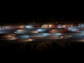 Aerial view over road traffic. Highway and overpass with cars and trucks, interchange, two-level road junction. Top view. Night shooting.