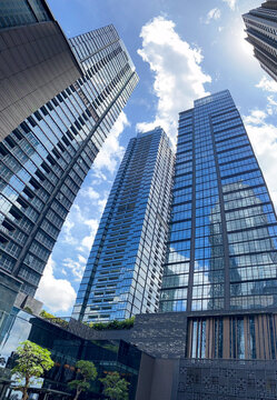 Jakarta, Indonesia - 09 November 2025: Dramatic low-angle view looking up at the glass facade of a towering modern skyscraper in District 8 SCBD with reflections of the clear sky.