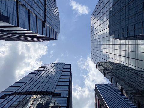 Jakarta, Indonesia - 09 November 2025: Dramatic low-angle view looking up at the glass facade of a towering modern skyscraper in District 8 SCBD with reflections of the clear sky.