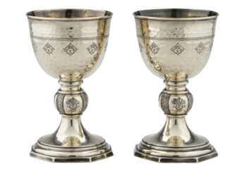 two ornate antique silver chalices, highly polished with hammered texture and repoussé detailing, displayed in a high-key studio product shot against transparent copy space. concept of ancient luxury
