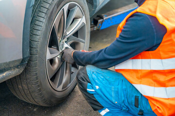 Mechanic using an impact wrench to remove lug nuts from a car wheel. Seasonal tire change and professional car service in preparation for winter.