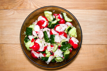 Summer Freshness: Radish and Cucumber Salad in a Clear Bowl on a Wooden Surface