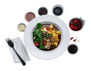 A bowl of colorful pasta with fresh vegetables and herbs surrounded by various seasonings and cherry tomatoes on a plate