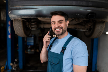 Mechanic communicating while working under a car at an auto repair shop in the afternoon