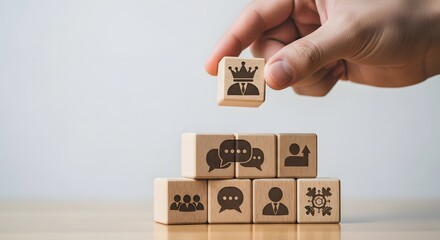 Leader placing king block on stacked wooden cubes with icons
