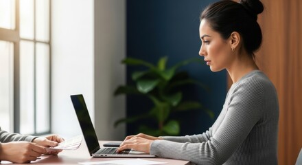 Professional Asian woman typing on laptop in a creative studio. Team collaboration on a design project. Selecting color palette from swatches for branding. Business meeting and consultation