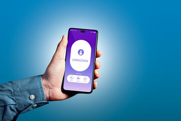 Hand holding smartphone receiving unknown incoming call