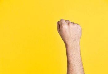 Raised fist symbolizing protest, power, and revolution against yellow background