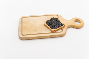 Feeta biscottata con confettura di mirtilli su un tagliere in legno, primo piano su fondo bianco