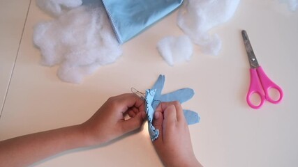 Top view. Children's hands hold a needle and thread and learn to sew.