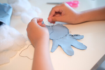 Top view. Children's hands hold a needle and thread and learn to sew.
