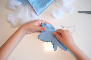 Top view. Children's hands hold a needle and thread and learn to sew.