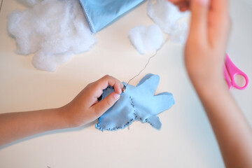 Top view. Children's hands hold a needle and thread and learn to sew.