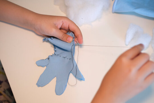 Top view. Children's hands hold a needle and thread and learn to sew. - Powered by Adobe