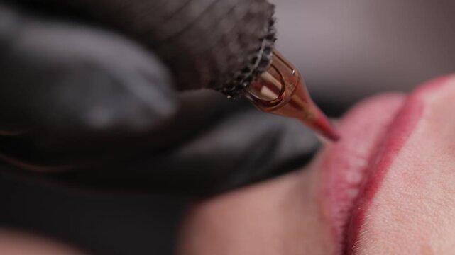 Top view Macro video process of applying microblading permanent makeup tattoo of red on lips woman.
