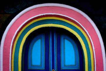 An arched doorway with a bright pink and yellow frame, set against a dark blue background, emphasizing cheerful architecture.