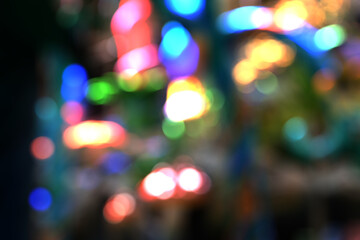 Heavily blurred colorful bokeh lights at night, creating an atmosphere of celebration, festival, or a party setting.