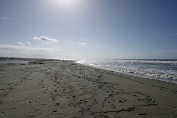 Mediterranean Beach at Tore del lago Puccini. Autumn sky with little sun. Reflections in water.