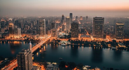 Expansive urban metropolis at twilight. Illuminated city skyline over a major river. Modern architecture and infrastructure development. Global business hub and financial district concept