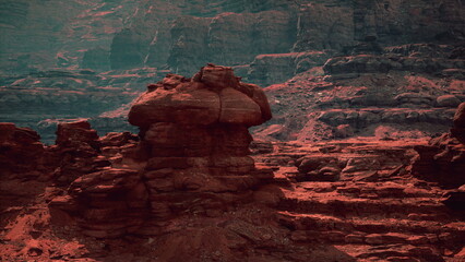 A scenic view captures unique rock formations bathed in red tones amid towering canyon walls. The setting sun creates shadows, enhancing the landscapes beauty.