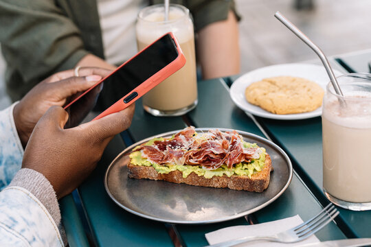 Multiethnic women enjoying brunch and using smartphone at outdoor cafe