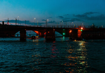 Venice, Italy - November 20, 2024: Nighttime view of a bridge illuminated with colorful lights, reflecting on the water, creating a serene atmosphere in an urban setting