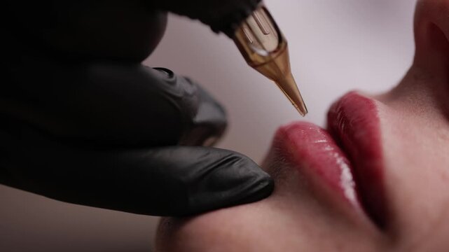 Fashion video of lip tattoo procedure on female lips with tattoo machine.