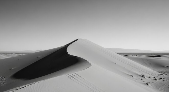 Dramatic black and white desert landscape. Minimalist sand dune with a sharp crest and deep shadow. Abstract natural forms and textures. Concept of journey, solitude and exploration